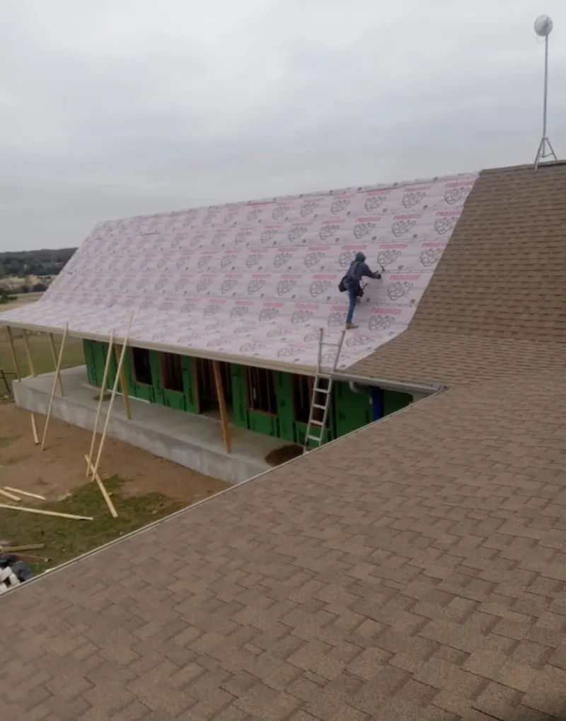 Worker preparing underlayment for a metal roof installation in Grosse Pointe